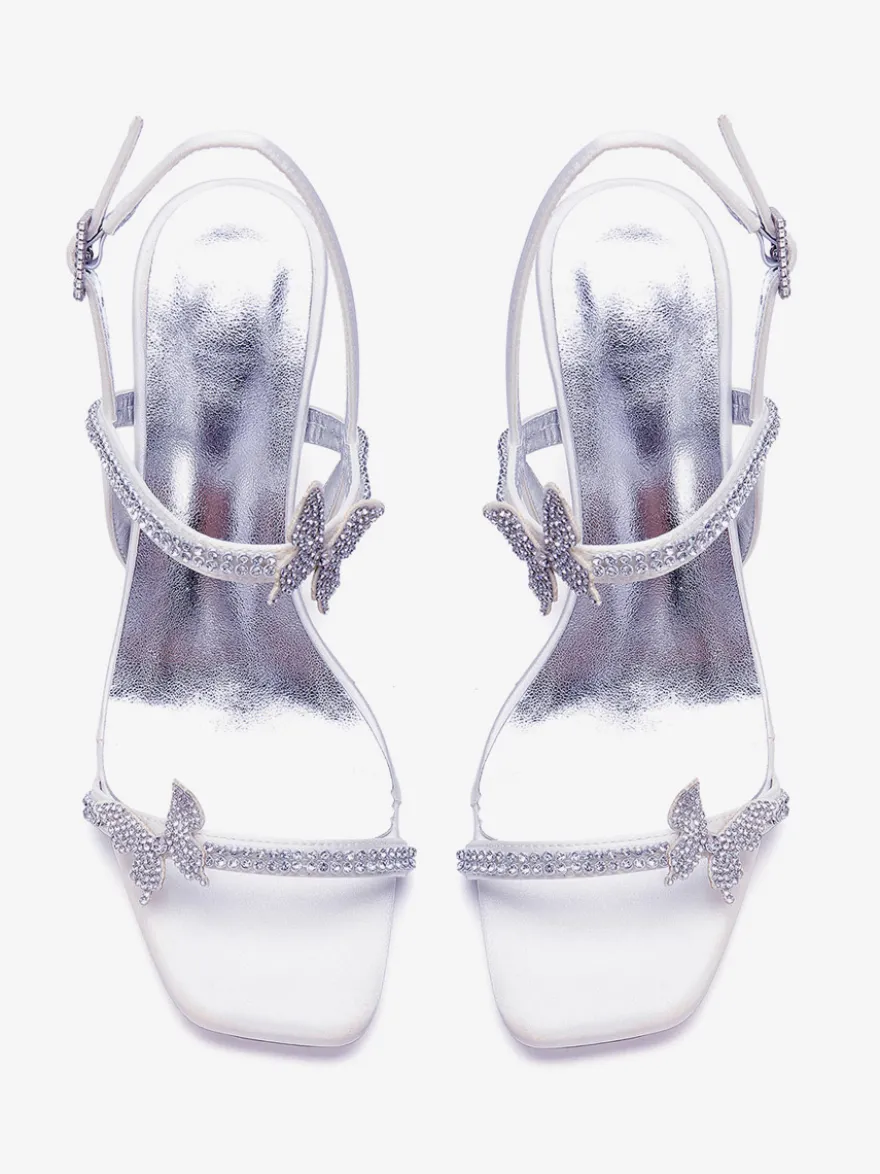 Chaussures de mariée blanches à talons compensés ornées de strass et de papillons bout ouvert.