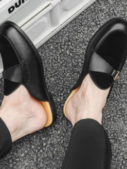 Mocassins noirs à bout rond avec détails métalliques et talon ouvert