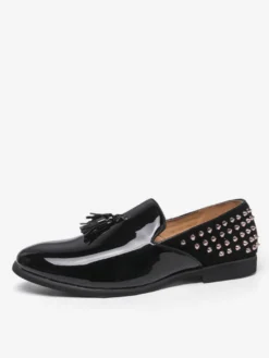 Mocassins noirs à bout rond pour homme ornés de rivets et de pompons.