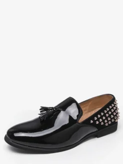 Mocassins noirs à bout rond pour homme ornés de rivets et de pompons.