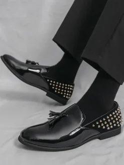 Mocassins noirs à bout rond pour homme ornés de rivets et de pompons.