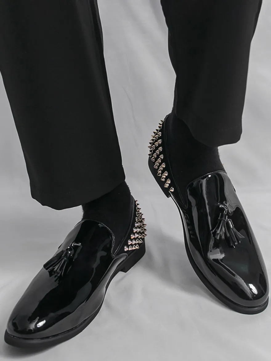 Mocassins noirs à bout rond pour homme ornés de rivets et de pompons.