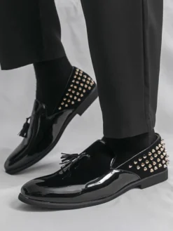 Mocassins noirs à bout rond pour homme ornés de rivets et de pompons.