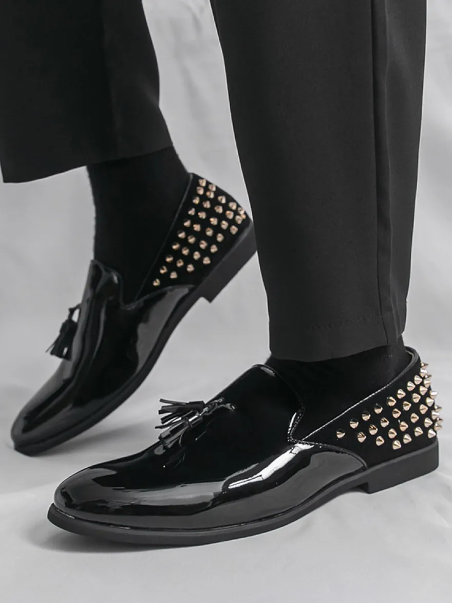 Mocassins noirs à bout rond pour homme ornés de rivets et de pompons.