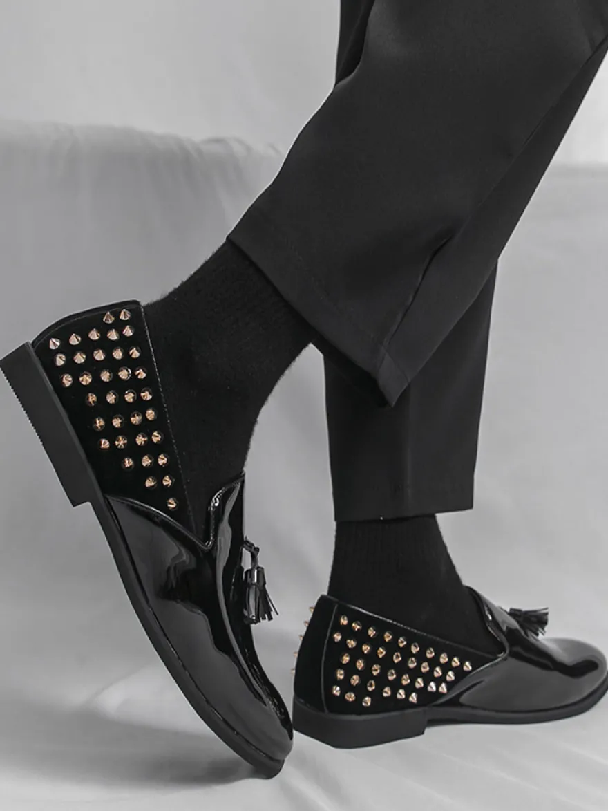 Mocassins noirs à bout rond pour homme ornés de rivets et de pompons.