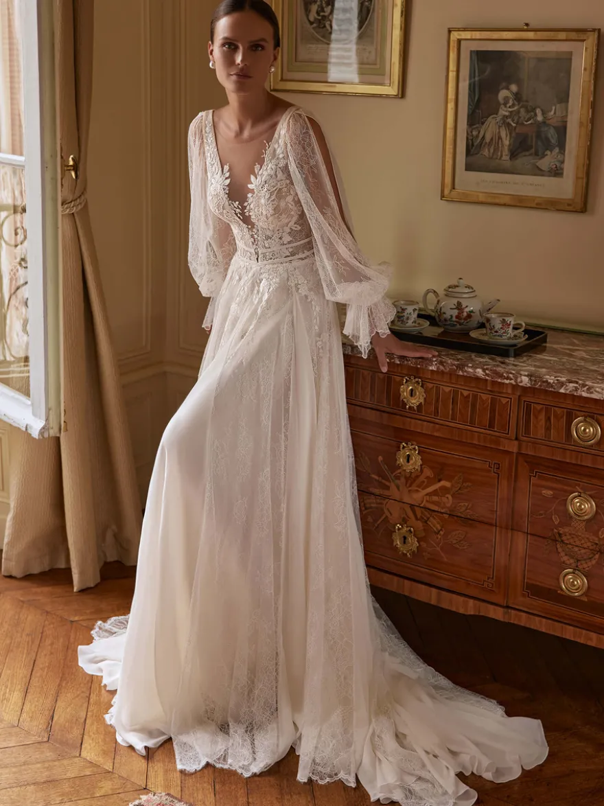Robe de mariée bohème en mousseline et dentelle coupe trapèze avec traîne taille naturelle fermeture éclair manches longues col en V blanche