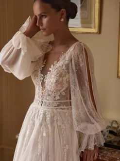 Robe de mariée bohème en mousseline et dentelle coupe trapèze avec traîne taille naturelle fermeture éclair manches longues col en V blanche