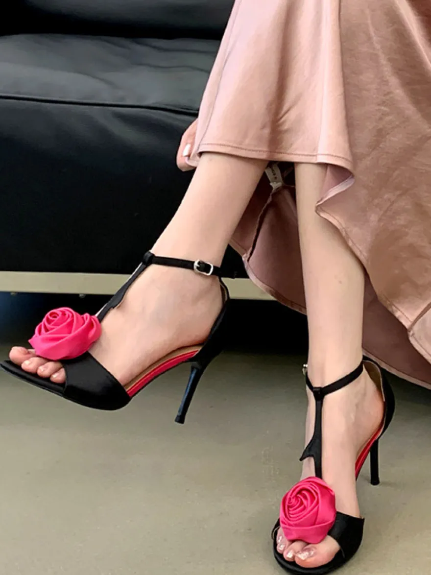 Sandales noires de soirée en satin à bout ouvert et détails floraux en forme de T à talons hauts.