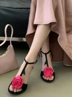 Sandales noires de soirée en satin à bout ouvert et détails floraux en forme de T à talons hauts.