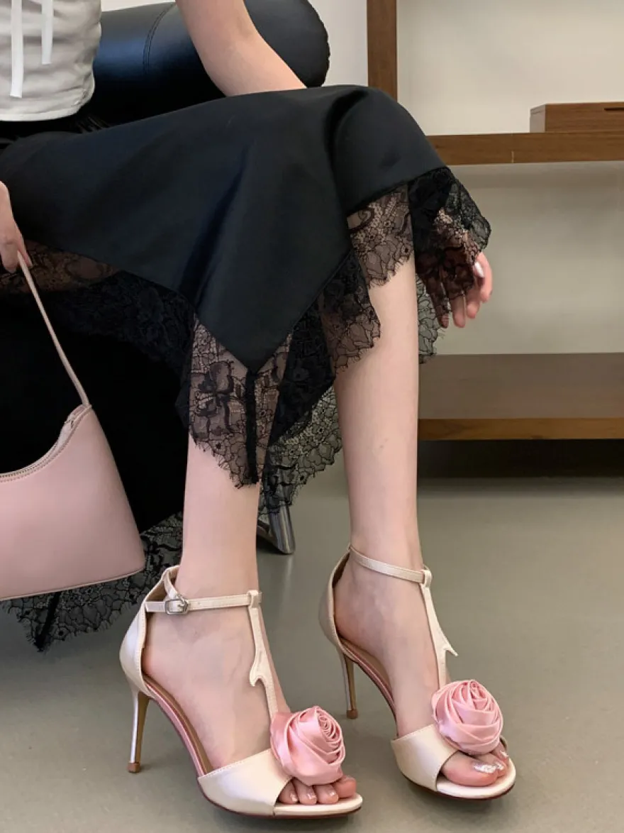 Sandales noires de soirée en satin à bout ouvert et détails floraux en forme de T à talons hauts.